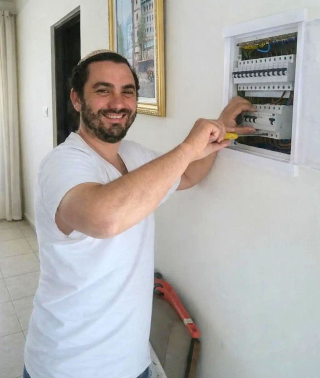 רונן בורוכוב מחייך ליד לוח חשמל